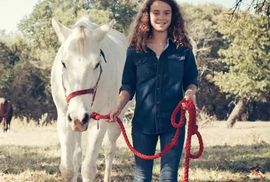 young girl with white horse on lead