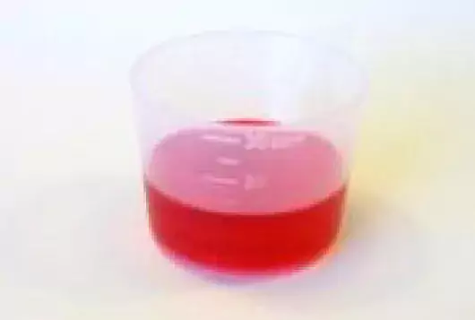 medicine measuring cup of red liquid 