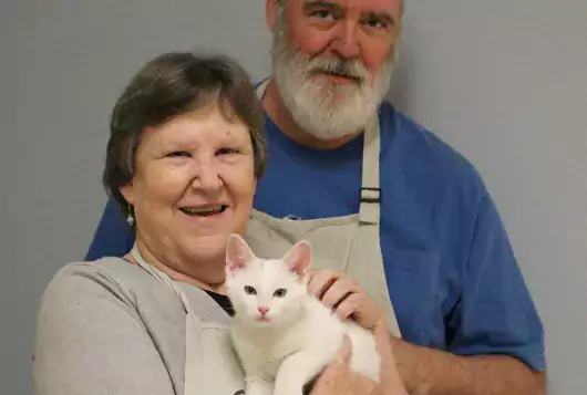 man and woman smiling with white cat