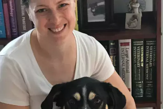 erin doyle in a room with books and black and white dog