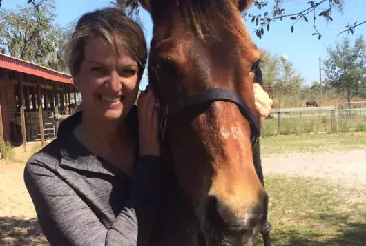 kelly ford poses outdoors with brown horse