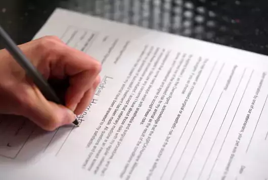 left-handed person signing a form