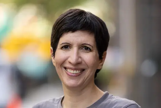 aspca staff member adi hovav wearing a gray and orange branded tee shirt outdoors